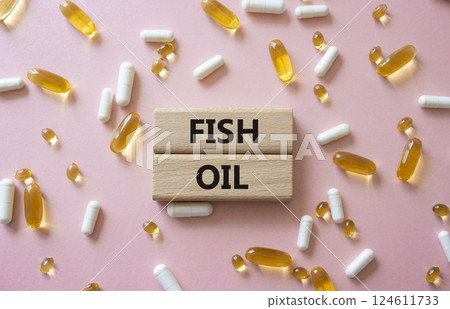 Fish Oil symbol. Concept word Fish Oil on wooden blocks. Beautiful pink background with pills. Medicine and Fish Oil concept. Copy space Fish Oil symbol. Concept word Fish Oil on wooden blocks. Beautiful pink background with pills. Medicine and Fish Oil concept. Copy space 124611733