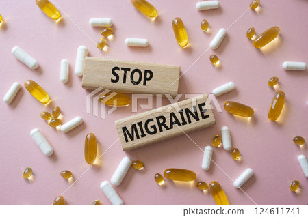 Stop Migraine symbol. Concept word Stop Migraine on wooden blocks. Beautiful pink background with pills. Medicine and Stop Migraine concept. Copy space Stop Migraine symbol. Concept word Stop Migraine on wooden blocks. Beautiful pink background with pills. Medicine and Stop Migraine concept. Copy space 124611741