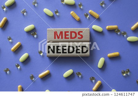Meds Needed symbol. Concept word Meds Needed on wooden blocks. Beautiful purple background with pills. Medicine and Meds Needed concept. Copy space 124611747