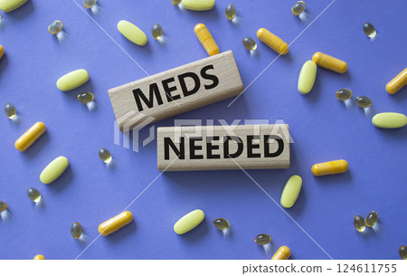 Meds Needed symbol. Concept word Meds Needed on wooden blocks. Beautiful purple background with pills. Medicine and Meds Needed concept. Copy space 124611755