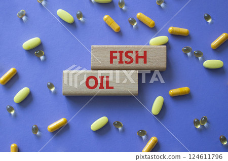 Fish Oil symbol. Concept word Fish Oil on wooden blocks. Beautiful purple background with pills. Medicine and Fish Oil concept. Copy space 124611796