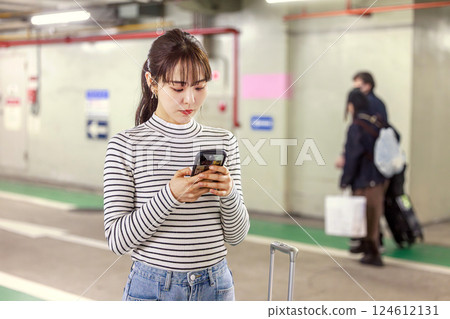 一名女子在地下通道裡看著她的智慧型手機 一名女子在地下通道裡看著她的智慧型手機 124612131