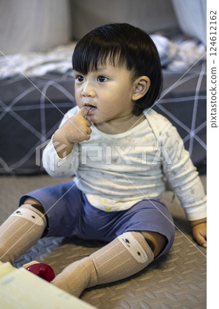Toddler In Baby Suit Putting Fingers In Mouth Toddler In Baby Suit Putting Fingers In Mouth 124612162
