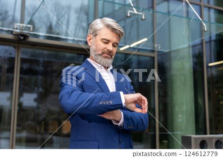 Bearded caucasian businessman looking at his watch while waiting for someone 124612779