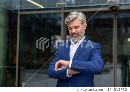 Bearded caucasian businessman looking at his watch while waiting for someone 124612780