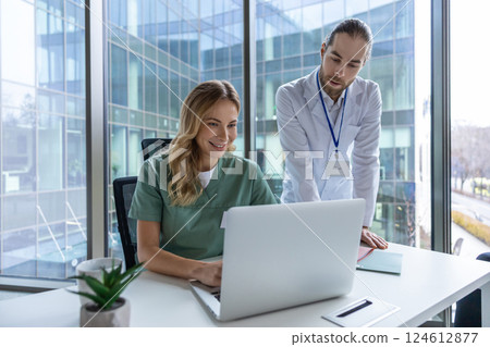 Man and woman doctors in hospital using technology for online consultation collaborating Man and woman doctors in hospital using technology for online consultation collaborating 124612877