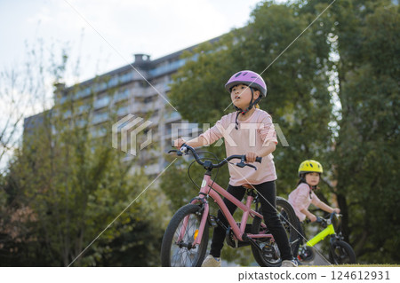 Sisters riding bicycles in the park 124612931