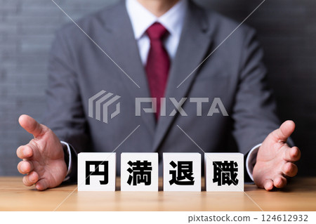 A middle-aged male businessman wearing a suit and a block of amicable retirement A middle-aged male businessman wearing a suit and a block of amicable retirement 124612932