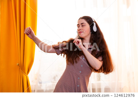 Woman dancing in a peaceful home environment, lost in sound and emotion. Mid shot 124612976