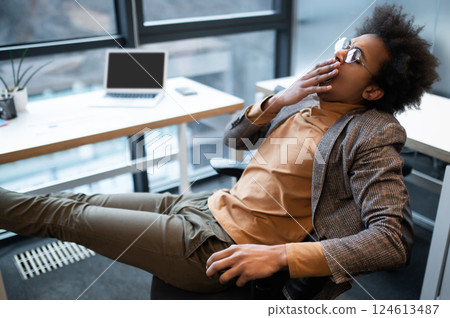 Man wearing suit sitting in office with big window 124613487