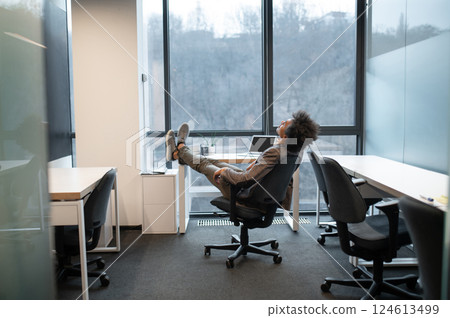 Businessman wearing suit sitting on armchair resting in modern office room 124613499
