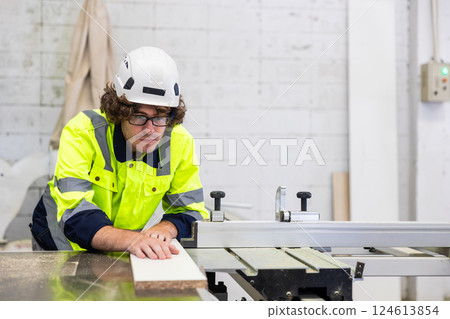 Professional employee male staff worker cutting wooden board on wood workbench in furniture factory 124613854