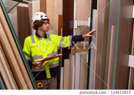 Male worker working in wood storage warehouse counting plywood panel stock inventory in workshop Male worker working in wood storage warehouse counting plywood panel stock inventory in workshop 124613855