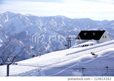 A view of the lift hut and snow-capped mountains from halfway up the ski resort 124614163