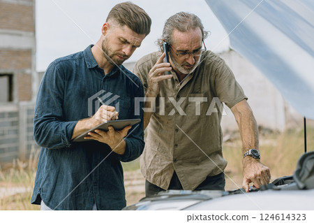 Senior male with car problem talking with auto service insurance assessment team at roadside 124614323