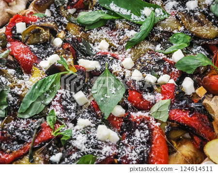 Colorful vegetable pizza topped with herbs and cheese served on a wooden board in a warm setting 124614511