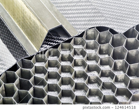 Close-up view of carbon fiber materials showcasing hexagonal honeycomb structures and metallic elements 124614518