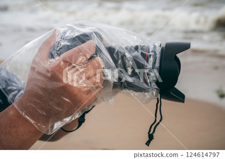 professional digital camera in waterproof case and a protective plastic bag against rain splashes in male hands of a photographer 124614797