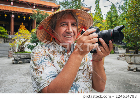 happy elderly man tourist travel photographer in Vietnamese hat takes pictures with camera at pagoda in Nha Trang in Vietnam. Tourism and travel in Asia happy elderly man tourist travel photographer in Vietnamese hat takes pictures with camera at pagoda in Nha Trang in Vietnam. Tourism and travel in Asia 124614798