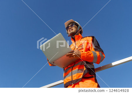 Asian engineer advance technology technician mechanic male standing with laptop computer on blue sky 124614928