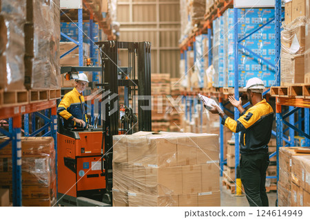Warehouse worker in duty stock control by forklift truck moving products cargo inventory management 124614949