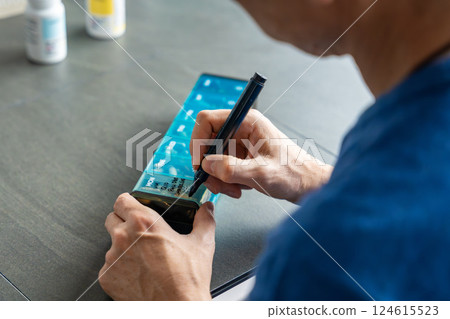 Man labeling compartments of his pill organizer with a permanent marker. Concept of organizing and personalizing medication management 124615523