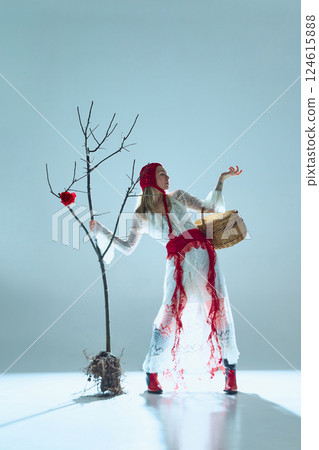 Woman in vintage-inspired lace dress with woven basket and bare tree creates striking contrast of nature and human existence. 124615888