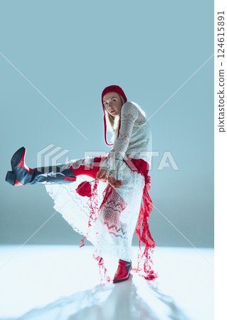 Young woman in white lace dress, red details, and statement boots kicks forward, eyes focused, embodying defiance and strength. Young woman in white lace dress, red details, and statement boots kicks forward, eyes focused, embodying defiance and strength. 124615891