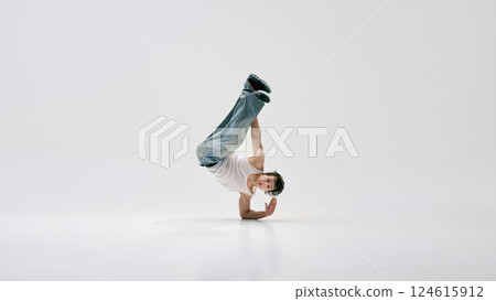 Talented hip hop dancer, dressed casual attire, lifting body into inverted pose with full control and dynamic posture against white background. Talented hip hop dancer, dressed casual attire, lifting body into inverted pose with full control and dynamic posture against white background. 124615912