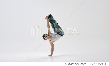 Artistic, talented dance performer twisting mid-motion showcasing impressive control and pure athleticism against white background. 124615931