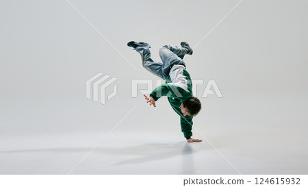 Urban artist, dressed retro attire, spinning into gravity-defying pose with body suspended in motion against white studio backdrop. Urban artist, dressed retro attire, spinning into gravity-defying pose with body suspended in motion against white studio backdrop. 124615932