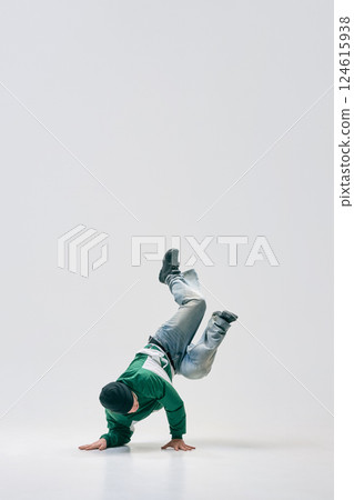 Breakdancer twisting mid-air while balancing on hands, showcasing flexibility and agility against white studio background. Breakdancer twisting mid-air while balancing on hands, showcasing flexibility and agility against white studio background. 124615938
