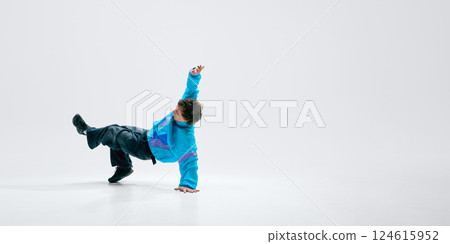 Breakdancer dressed stylish vintage clothes, executing headstand freeze, legs kicked high, against white background. 124615952