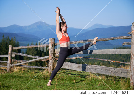 Woman practicing yoga outdoors in the mountains in a serene, natural setting. Female performing yoga pose, with backdrop of beautiful mountain landscape at sunrise or sunset. Woman practicing yoga outdoors in the mountains in a serene, natural setting. Female performing yoga pose, with backdrop of beautiful mountain landscape at sunrise or sunset. 124616213