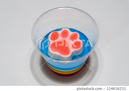 Colorful Layered Dessert Jelly Cup with Paw Shaped Topper on White Background Colorful Layered Dessert Jelly Cup with Paw Shaped Topper on White Background 124616231