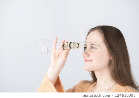 Portrait of beautiful woman watching through binoculars 124616395
