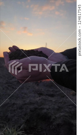 man holds land in his hands for planting agricultural crops. Soil and Agriculture. Farmer hands holding organic soil against the background of sunset. Concept of agribusiness. 124617545