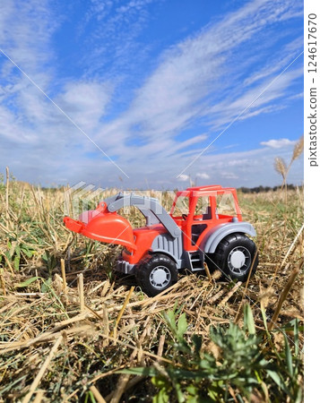 A red tractor is a toy in a harvested cornfield. Agricultural industry. A harvesting company. A red tractor is a toy in a harvested cornfield. Agricultural industry. A harvesting company. 124617670