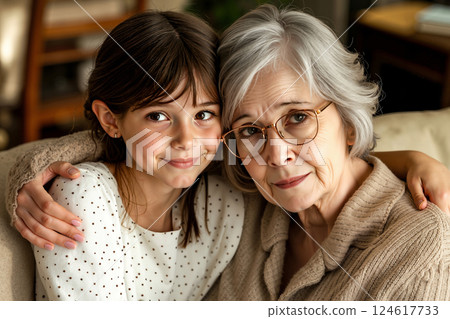 An older woman and a young girl sitting on a couch 124617733