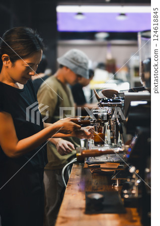 Shot in low light of female barista making a fresh coffee in cafe. 124618845