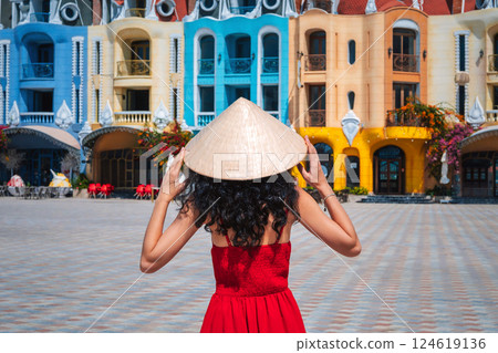 female tourist traveler in Vietnamese hat takes in sights on Vinpearl Island at VinWonders Amusement Park in Nha Trang at summer vacation in Asia. Travel and tourism in Vietnam 124619136