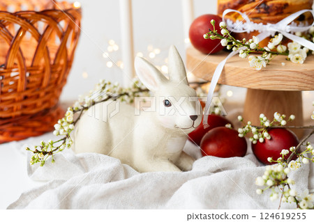 A cozy setting with a ceramic bunny, fresh pastries, and flowers, evoking a warm, homely atmosphere. Easter holiday concept. 124619255