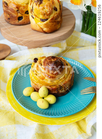 Delightful Easter sweet bread, a traditional treat, is presented on a vibrant blue plate, adorned with pastel yellow eggs. Perfect for spring celebrations 124619256