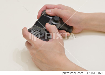 Hands operating a game with a controller 124619460