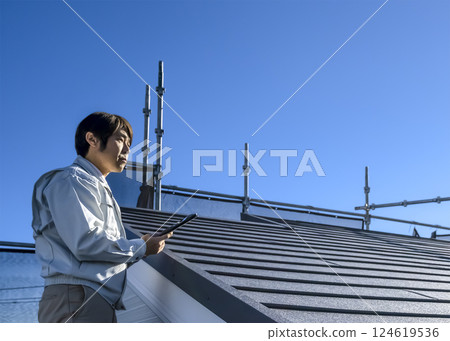 A man checking the progress of roof repair work on a detached house A man checking the progress of roof repair work on a detached house 124619536