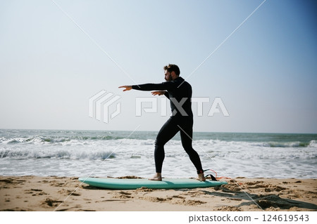 Surfer Practicing Poses on Beach Sand 124619543
