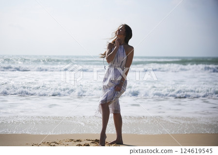Woman Standing Gracefully by Ocean Waves Woman Standing Gracefully by Ocean Waves 124619545