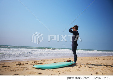 Surfer Scanning Waves on Sunny Beach 124619549