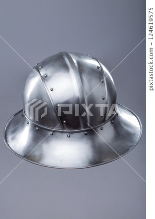Silver Helmet with Wide Brim and Rivets. This image shows a shiny silver helmet featuring a wide, downward-sloping brim and several small rivets along its edges and the crown. 124619575