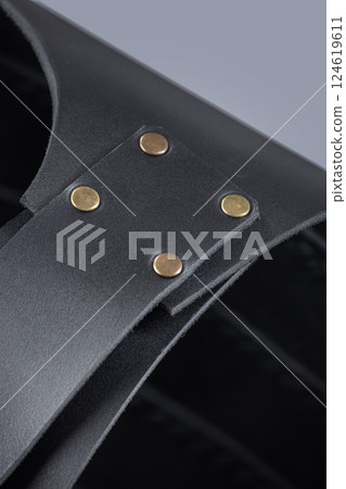 Close-up of Leather Shoulder Straps on Black Cuirass. Detailed view of the black leather armor showing the shoulder straps and brass rivet fastenings. Close-up of Leather Shoulder Straps on Black Cuirass. Detailed view of the black leather armor showing the shoulder straps and brass rivet fastenings. 124619611